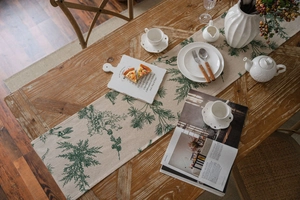 Detail of pine needle printed cotton linen table runner on a solid wooden dining table