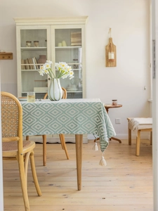 Close-up of sage green and white diamond pattern tablecloth with elegant cream tassels