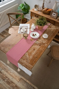 Detail of red and white striped table runner with decorative off-white fringe tassels