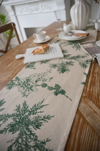 Close-up of pine needle print table runner with rustic tassels on wooden dining table