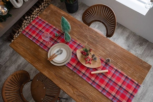 Detail of red and blue plaid table runner with high-quality woven fabric texture and pine cones