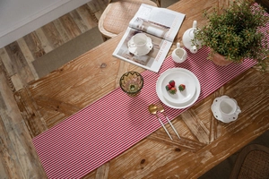 Macro detail of red and white striped cotton table runner on a rustic wooden table