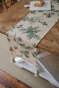 Detail of pine branch and bird print on linen table runner with tassel fringe
