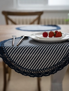 Detail of round placemat with blue and white stripes and elegant crochet lace border