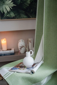 Detail of green linen cafe curtain with white stripes on a decorated wooden table