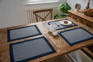 Detail of blue and white striped cotton placemats with delicate lace crochet borders