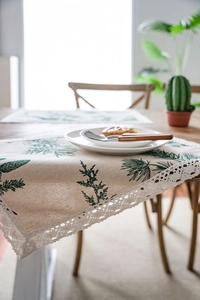 Close-up of cotton linen table runner featuring pine needle prints and white lace edges