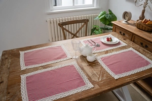 Set of 4 red striped table mats with delicate cream lace borders on a wooden dining table