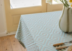 Detail of green jacquard geometric diamond tablecloth with woven texture and soft drape
