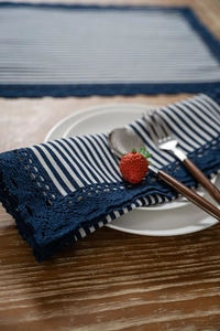 Close-up of blue and white striped table napkin with elegant crochet lace edge detail