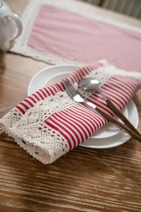 Detail of red and white striped table napkin with elegant beige crochet lace edging decoration