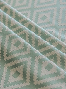 Close-up of mint green and cream jacquard tablecloth featuring geometric diamond patterns