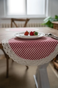 Detail of red and white striped table runner with white crochet lace border on a wooden table