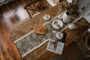 Dettaglio del runner da tavola vintage verde floreale con frange su un tavolo di legno scuro