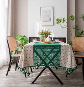 Detail of blue daisy tablecloth with dark green hollow crochet runner and tassels