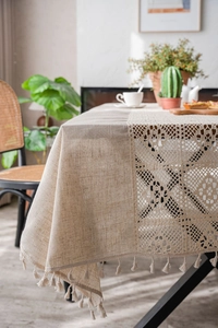 Close-up of minimalist beige linen tablecloth featuring hollow lace stitching and tassel fringe