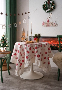 Detail of round Christmas tablecloth featuring red festive patterns and ruffle edges