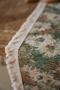 Dettaglio del runner da tavolo jacquard floreale vintage con frange su legno