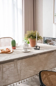Close-up of linen tablecloth featuring delicate lace patchwork and tassel edges