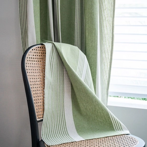 Green and white striped cotton linen curtain in American style draped over a chair