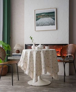 Detailed view of cream ruffle edge tablecloth with yellow floral print in a cozy dining room