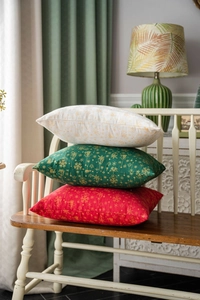 Three Christmas pillow covers in green, red, and beige with golden festive foil patterns