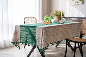 Detail of blue daisy tablecloth with forest green crochet lace and fringe tassels