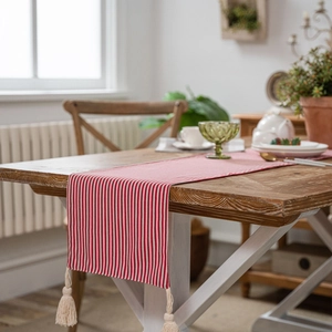 Red and white striped table runner with tassel ornaments in a warm home setting