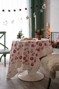 Close-up of festive tablecloth with red ruffle edges and Christmas ornament prints