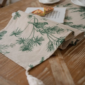 Linen table runner with pine cone and bird print featuring elegant fringe trim