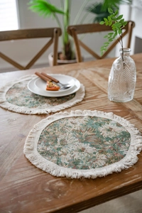 Dettaglio di tovagliette tonde con motivi broccati floreali e nappe in cotone