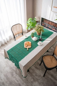 Detail of blue floral tablecloth with green hollow crochet runner and elegant tassels