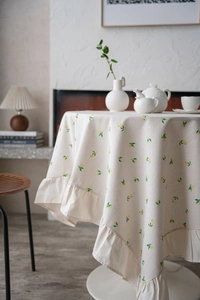 Detail of round linen tablecloth with yellow lemon print and elegant ruffled edges