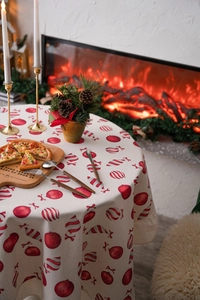 Detail of round Christmas tablecloth with festive red ornament prints on cream fabric