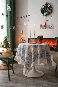 Detail of round cream tablecloth with vintage floral print and ruffled hem for Christmas