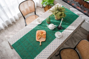 Detail of blue polka dot tablecloth with dark green hollow lace runner and tassel accents
