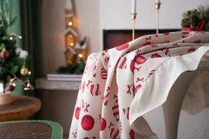 Close-up of festive tablecloth featuring red Christmas ornaments and elegant ruffle edges