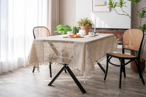 Detail showing beige hollowed lace patchwork and fringe tassels on linen tablecloth
