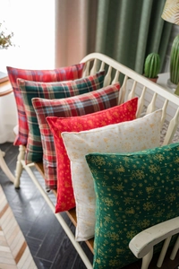 Detailed view of festive British plaid and Christmas print cushion covers on a wooden bench