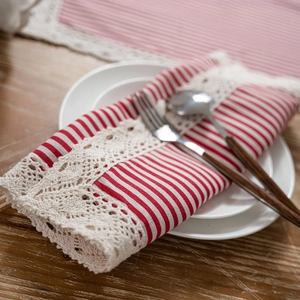 Red and white striped placemat with delicate lace trim on a rustic wooden table