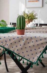 Detail of blue floral cotton linen tablecloth with green crochet lace and fringe tassels