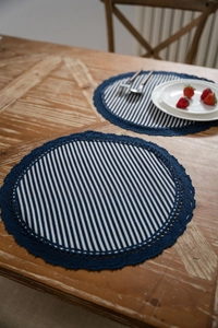 Dettaglio della tovaglietta rotonda con strisce blu e bordo in pizzo all'uncinetto