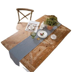 Blue and white striped linen table runner with tassels on a wooden dining table