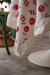Close-up of Christmas tablecloth showing red ornaments print and ruffled edge detail