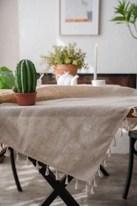 Detailed view of linen tablecloth with handcrafted fringe edges on a wooden table