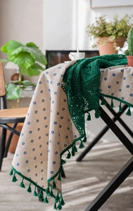 Detail of blue daisy floral tablecloth with green crochet lace and fringe tassels