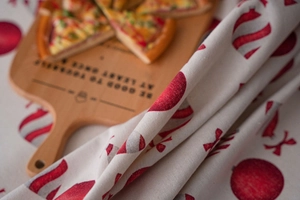 Detail of red Christmas ornaments and bow patterns on textured cotton linen tablecloth