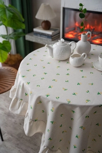 Detail view of round tablecloth with lemon prints and elegant ruffled edge