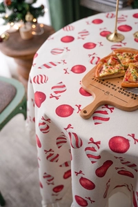 Close-up of Christmas tablecloth with red ornaments print and elegant beige tassels