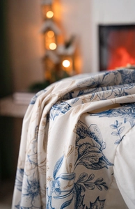 Close-up of pine cone and floral printed tablecloth with warm festive lighting background